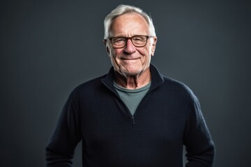 Obraz premium Portrait of a senior man wearing glasses on a gray background.