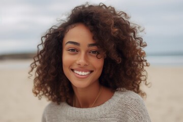 Close up portrait of a beautiful young african american woman with curly hair smiling on the beach