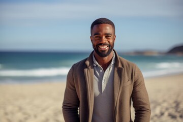 Portrait of smiling man standing on beach with hand in pocket looking at camera
