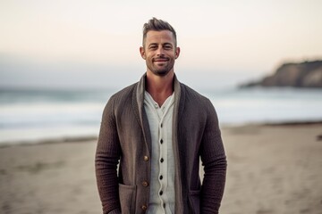 Portrait of a handsome man standing on the beach at the sunset