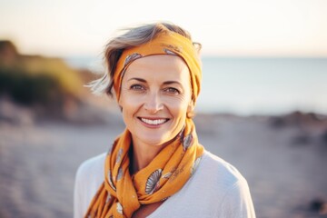 Portrait of smiling mature woman wearing scarf on the beach at sunset