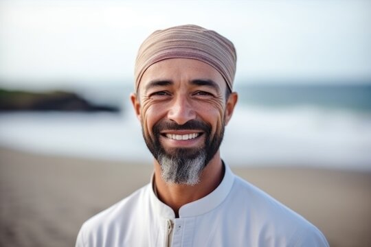 Portrait of smiling muslim man with headscarf on the beach