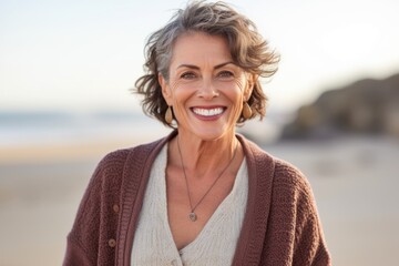 Portrait of smiling mature woman standing on beach at the day time