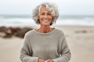 Fototapeta na wymiar Portrait of a happy senior woman standing on the beach with arms crossed