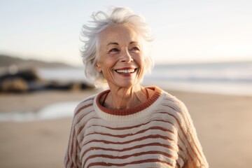 Portrait of smiling senior woman standing on beach at the day time