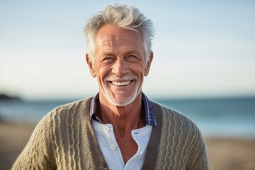 Medium shot portrait photography of a grinning man in his 60s wearing a chic cardigan against a beach background