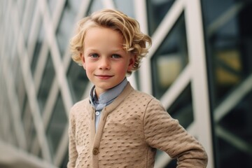 Portrait of a cute little boy with blond curly hair in a beige coat.