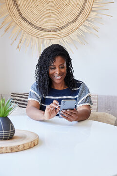 Mature Black woman laughing smiling and texting on phone at home