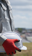 ヘルメットを持つ作業服の男性｜建設業・製造業などのイメージ