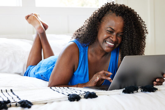 Mature Black Woman On Computer At Home In Bed In Bedroom Smiling