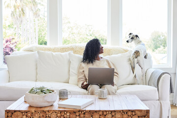 Mature Black woman on computer at home on sofa connecting with p