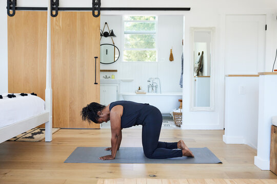 Mature Black woman in table pose doing yoga at home