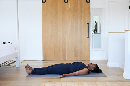 Mature Black woman in relaxation pose doing yoga at home
