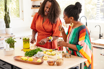 Mature Black women friends cooking and laughing together in kitchen