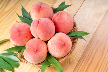 White Peaches with leaves on the wooden table, Fresh Japan Peach wooden basket plate in wooden...