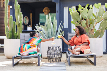 Mature Black women friends doing a toast with drinks at resort