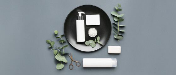 Set of bathing cosmetics with scissors and eucalyptus on grey background