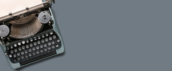 Vintage typewriter with paper sheet on grey background. Banner for design