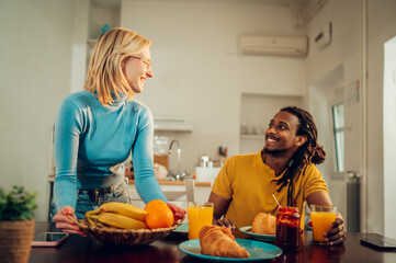 A happy multiracial family is having breakfast at home.