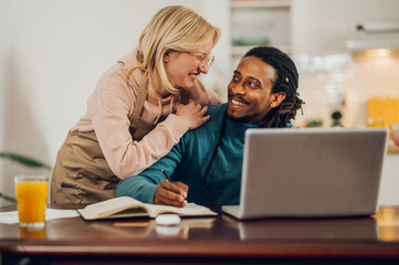 A happy interracial couple in love smiling at each other at home.