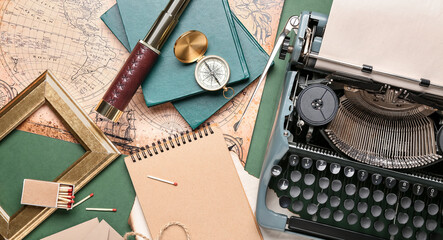 Vintage typewriter, spyglass, compass, books and old map on green background