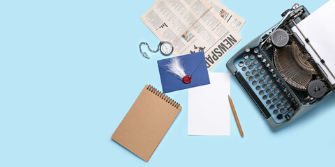 Vintage typewriter, envelope, pocket watch, notebook, newspapers and paper sheet on light blue...