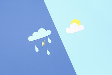 Paper clouds with rain drops, lightning and sun on blue background. Weather forecast concept