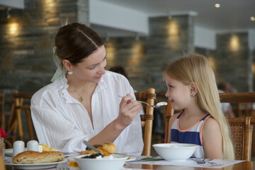 Mother is feeding her daughter in the restaurant