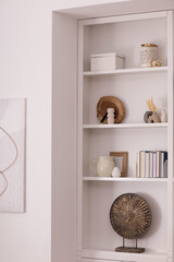 Stylish shelves with different decor elements in room. Interior design