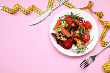 Healthy salad with measuring tape on pink background, flat lay and space for text. Diet concept