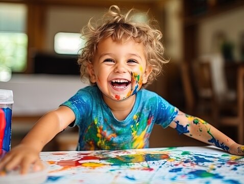 smiling young boy with bright paint on his hands and body