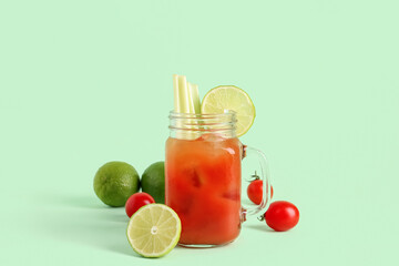 Mason jar of bloody mary with celery and lime on green background © Pixel-Shot
