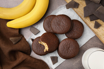 Tasty banana choco pies, pieces of chocolate and fruits on textured table, flat lay