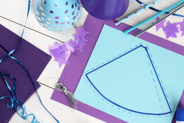 Flat lay composition with different materials to create party hats on white wooden table. Handmade decoration