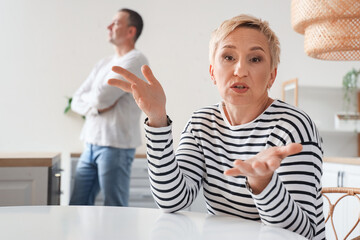 Mature woman quarreling with her husband in kitchen