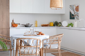 Interior of modern kitchen with dining table and white counters