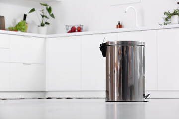 Metallic trash bin in interior of light kitchen