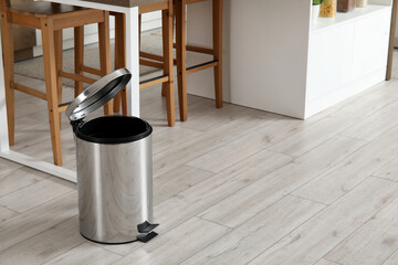 Opened trash bin in interior of light kitchen