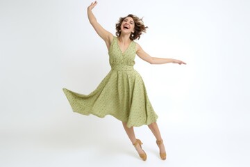 Young woman in green dress dancing on white background. Studio shot.