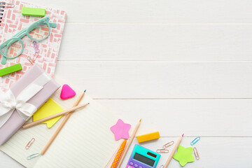 Gift box with calculator, eyeglasses and different stationery on white wooden background