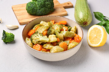 Bowl with different vegetables on light background