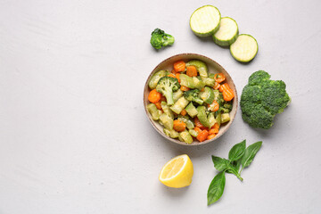 Bowl with different vegetables on light background