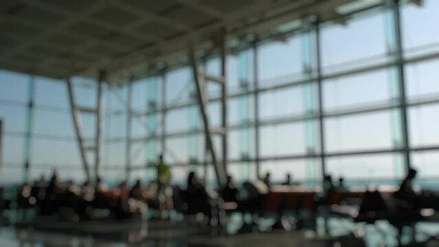 Silhouettes of passengers waiting and walking in front of the boarding gates at Izmir Airport.
