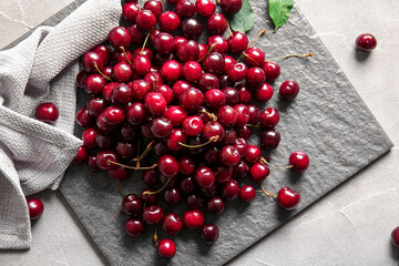 Board with sweet cherries on grey table