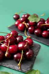 Boards with sweet cherries on green background