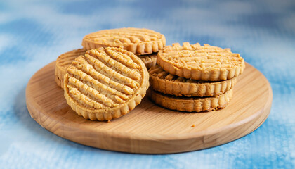 Peanut butter cookies stack on wooden cutting board. Traditional american dessert, nutrition snack, dessert or breakfast food. Blue and white background. Closeup food. Criss cross patterned biscuits.