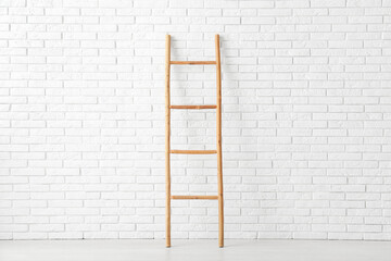 Wooden ladder near white brick wall in room