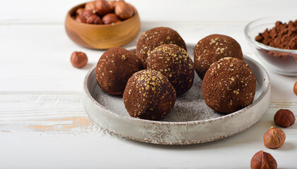 Energy balls. Healthy raw dessert (bliss balls), vegetarian truffles, sugar free candies made of dates, hazelnuts, cocoa powder. Step by step cooking. White wooden background.
