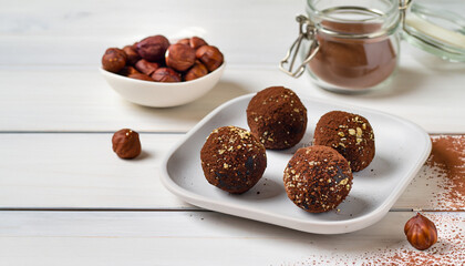 Energy balls. Healthy raw dessert (bliss balls), vegetarian truffles, sugar free candies made of dates, hazelnuts, cocoa powder. Step by step cooking. White wooden background.
