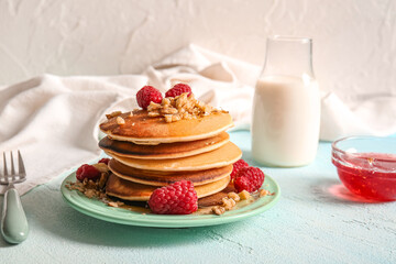 Plate of tasty pancakes with raspberries on light background
